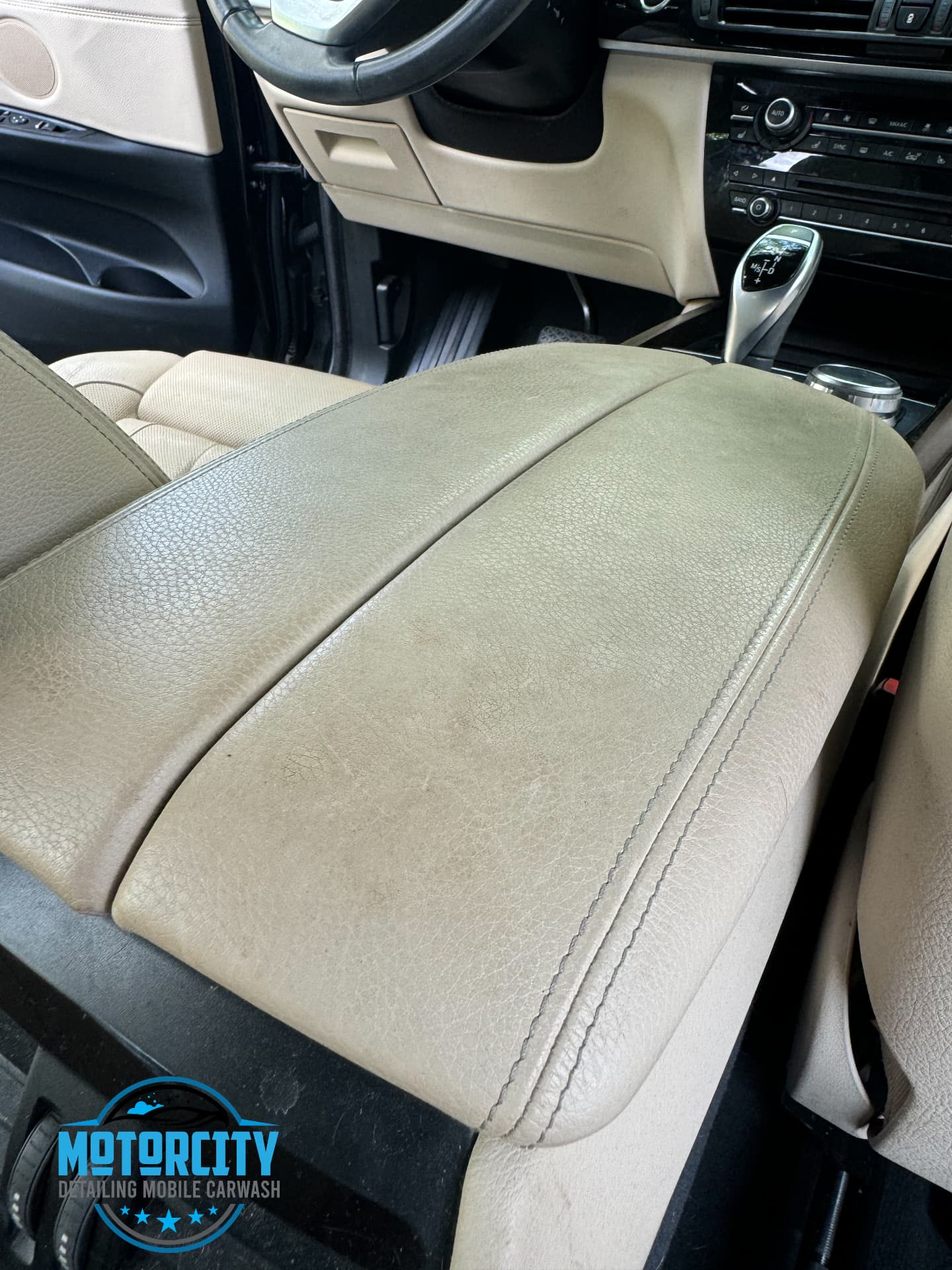 Beige leather driver seat and console cleaned during interior detailing