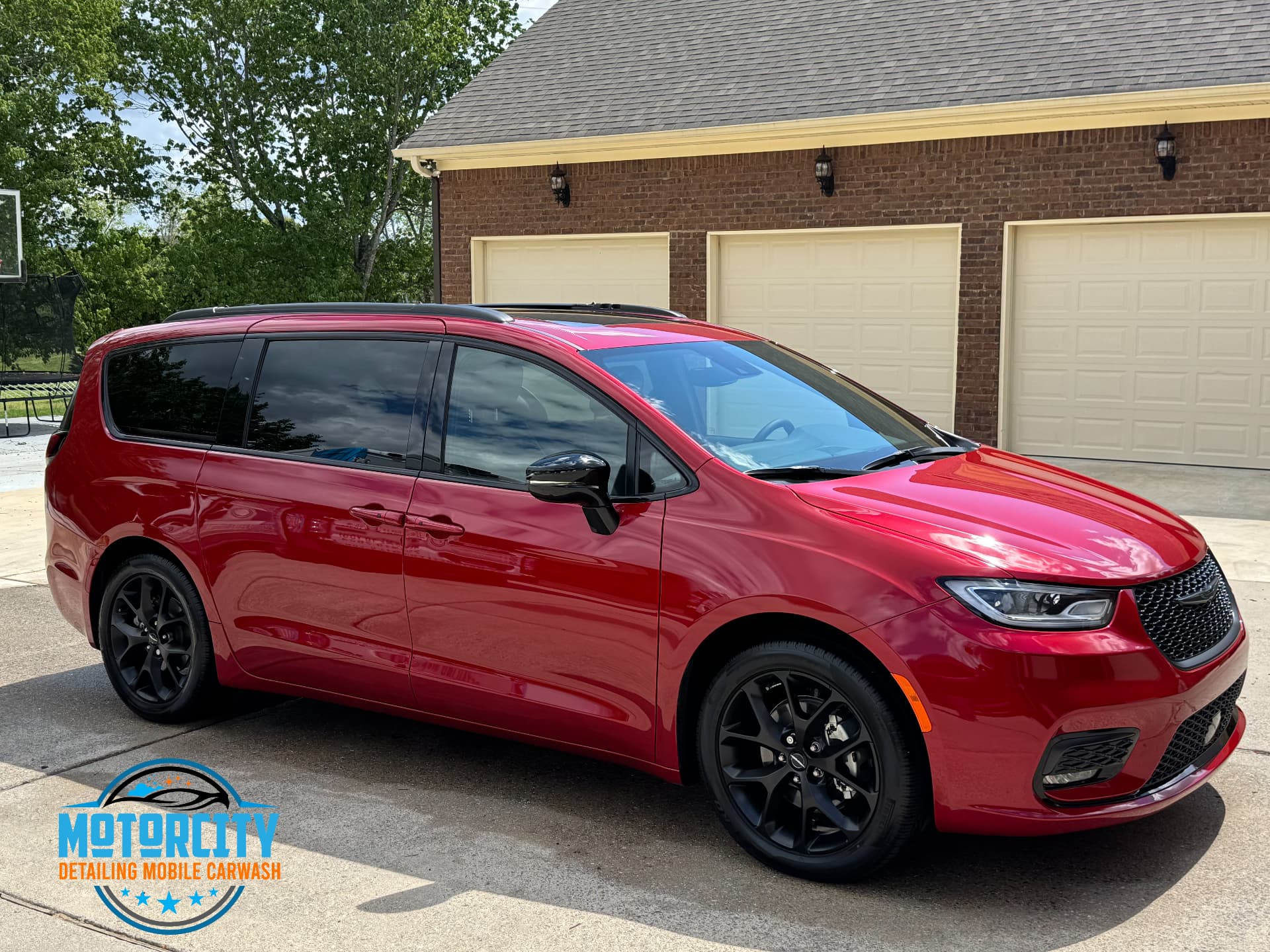 Red Chrysler Pacifica minivan detailed in a family driveway